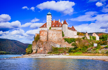 Austria, Schonbuhel Castle stands atop a rocky cliff, surrounded by golden autumn foliage, overlooking the Danube River, Wachau Valley.