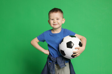 Cute little boy with soccer ball on green background