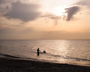 Fototapeta premium People Silhouetted in the Ocean at Sunset