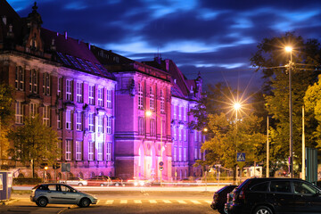 Historic building illuminated with purple light at night. Nighttime Cityscape with Illuminated Buildings and Car - Szczecin Poland.