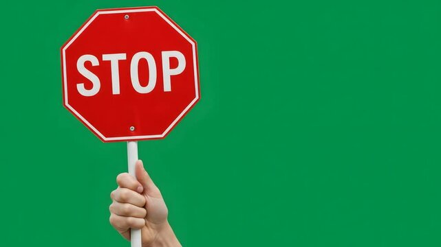 Handheld red stop sign against green background