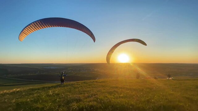 Paragliders on a hill at sunset