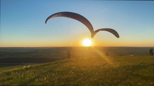 Paragliders on a hill at sunset