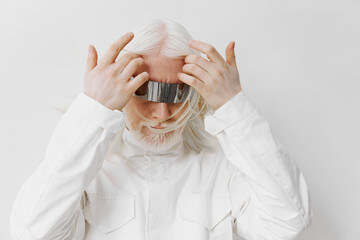 Futuristic portrait of a person with long white hair wearing sleek metallic headgear, set against a...