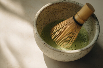 ceramic bowl with frothy matcha and bamboo whisk creates serene tea making scene