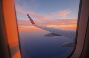 Obraz premium Aerial view through aircraft window at sunset with wing