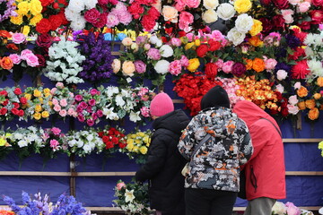 Women choose artificial ritual flowers at the market ahead of Easter