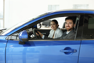 Happy saleswoman and client inside new car in salon