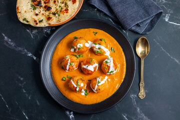 Soft, creamy malai kofta in rich, spiced tomato-cashew gravy, perfectly paired with warm, fluffy butter naan—an indulgent North Indian delight bursting with flavour and aroma.