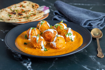 Soft, creamy malai kofta in rich, spiced tomato-cashew gravy, perfectly paired with warm, fluffy butter naan—an indulgent North Indian delight bursting with flavour and aroma.