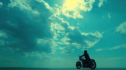 A silhouette of a motorcyclist cruising along a coastal road under a dramatic sky at sunset