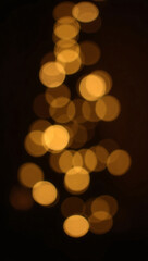 Golden bokeh lights shaped like a Christmas tree against a dark background, creating a festive, blurred effect