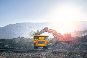 Excavator loads coal into large yellow dump truck on open pit mine. Industry mining on winter career © Parilov