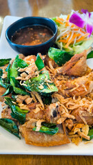 Fried chicken wings in a white plate on a wooden table decorated with orchids.