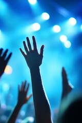 Silhouetted hands raised high at a concert, illuminated by bright stage lights.