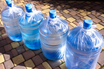 Delivery of drinking filtered water, 19l bottles filled with water stand in a row.