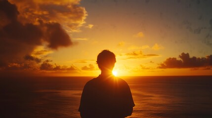 Silhouette of person standing on beach watching dramatic sunset over ocean horizon with vibrant orange sky and cloud formations, copy space