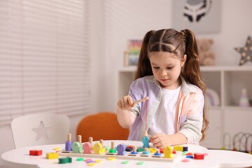 Motor skills development. Little girl playing with math game Fishing for Numbers at white table...