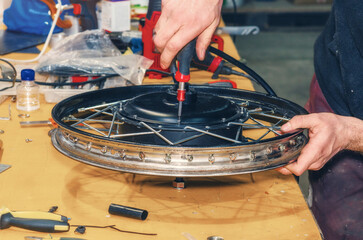 Bicycle mechanic tightens cover on electric motor using screwdriver. Electric bicycle repair. Workshop.