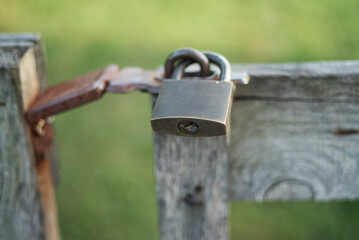   A locked metal padlock secured on a wooden gate