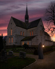 Ein verh&uuml;llte Gestalt steht mit einer beleuchteten Laterne auf der R&uuml;ckseite vom Kloster Loccum am Abend im Sonnenuntergang