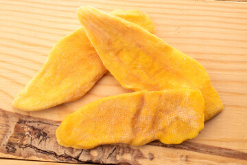 Dried mango slices on a wooden table, close-up, top view.