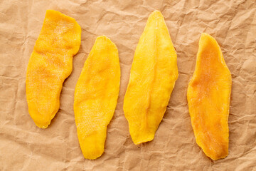 Dried mango slices on kraft paper, macro, top view.