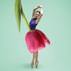 Young ballerina dancing on aquamarine color background. Tulip flower partly covering woman as skirt
