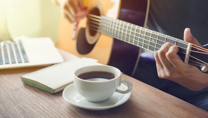 Fototapeta premium A cup of coffee and hands playing a guitar