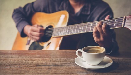 A cup of coffee and hands playing a guitar