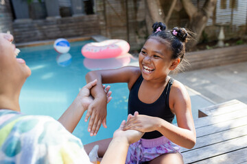 Happy mother and daughter splashing in outdoor swimming pool, enjoying inflatable floaty fun
