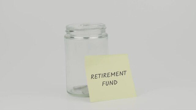 A hand inserts a coin into an empty glass jar labeled with yellow sticky notes reading "Retirement Fund," then seals the lid, all set against a clean white background