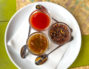 Three small bowls of condiments on a white plate