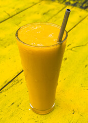 A glass of orange juice with a straw in it