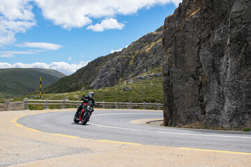 One biker driving on a red motorcycle on a mountain road in a national park in the north portugal. Curve in the road. Exploring, roadtrip summer vacation. Scenic driving