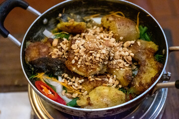 Detailed top-down view of a Vietnamese noodle bowl with grilled meat, spring rolls, vegetables, and crushed peanuts in Ninh Binh, Vietnam, on December 26, 2019