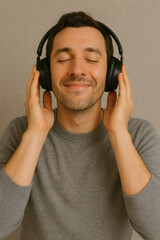 Fototapeta premium man holding his headphones listening to music with an expression of pleasure and peace