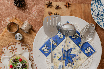 close up of spatula, a ladle, and a perforated spoon on plate.Brown and blue Decorated christmas...