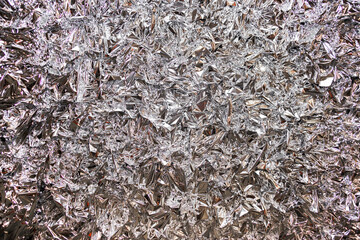 A close-up of the texture of a pressed foil or a silver-colored polysilk.