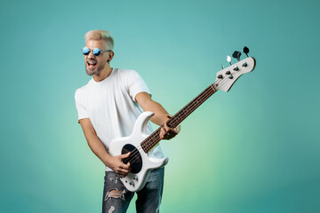 Hipster man play white bass guitar over colorful background. Rock music concept