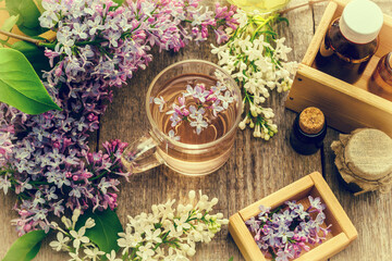 Essential oil and a cup of tea made from lilac flowers