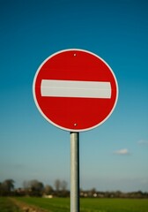 No Entry Traffic Sign on Rural Road with Clear Blue Sky.