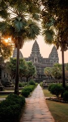 Fototapeta premium Angkor Wat at Sunrise: A majestic view of the ancient Angkor Wat temple, bathed in the soft, golden light of sunrise. Pathway leading towards the temple amidst lush greenery.
