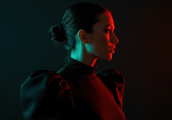 A stylish woman's profile is artfully lit with vibrant red and green hues on a dark background.