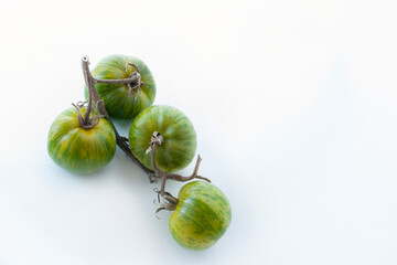 Green striped tomatoes with yellow stripes on a white background. Photo for a banner.