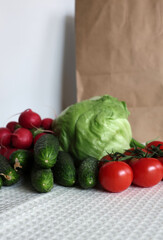 A vibrant image displaying a fresh selection of vegetables purchased at a local farmer's market, including crisp iceberg lettuce, bright red radishes, crunchy cucumbers, and ripe tomatoes.