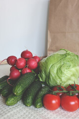 A vibrant image displaying a fresh selection of vegetables purchased at a local farmer's market, including crisp iceberg lettuce, bright red radishes, crunchy cucumbers, and ripe tomatoes.