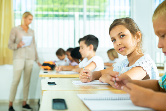 Portrait of cheerful preteen girl elementary school student looking at camera during lesson