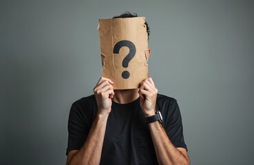 Anonymous person covers head with cardboard sheet, question mark drawn on paper. Incognito man hiding identity. Concept of mystery, uncertainty, decision making, unknown, doubt, introversion.