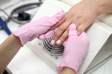 A gloved manicurist waxes a woman's hands after a manicure at a nail salon. Professional hand massage. Relaxing hand massage. A girl gets a relaxing hand massage